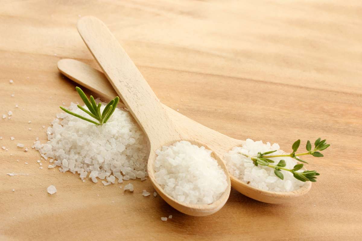 Nadmiar soli w organizmie pokazany za pomocą dwóch łyżek, z których wysypuje się sól.